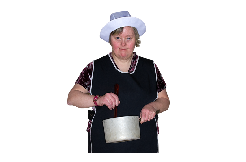 A woman wearing an apron and cooks hat stirring a pan. 